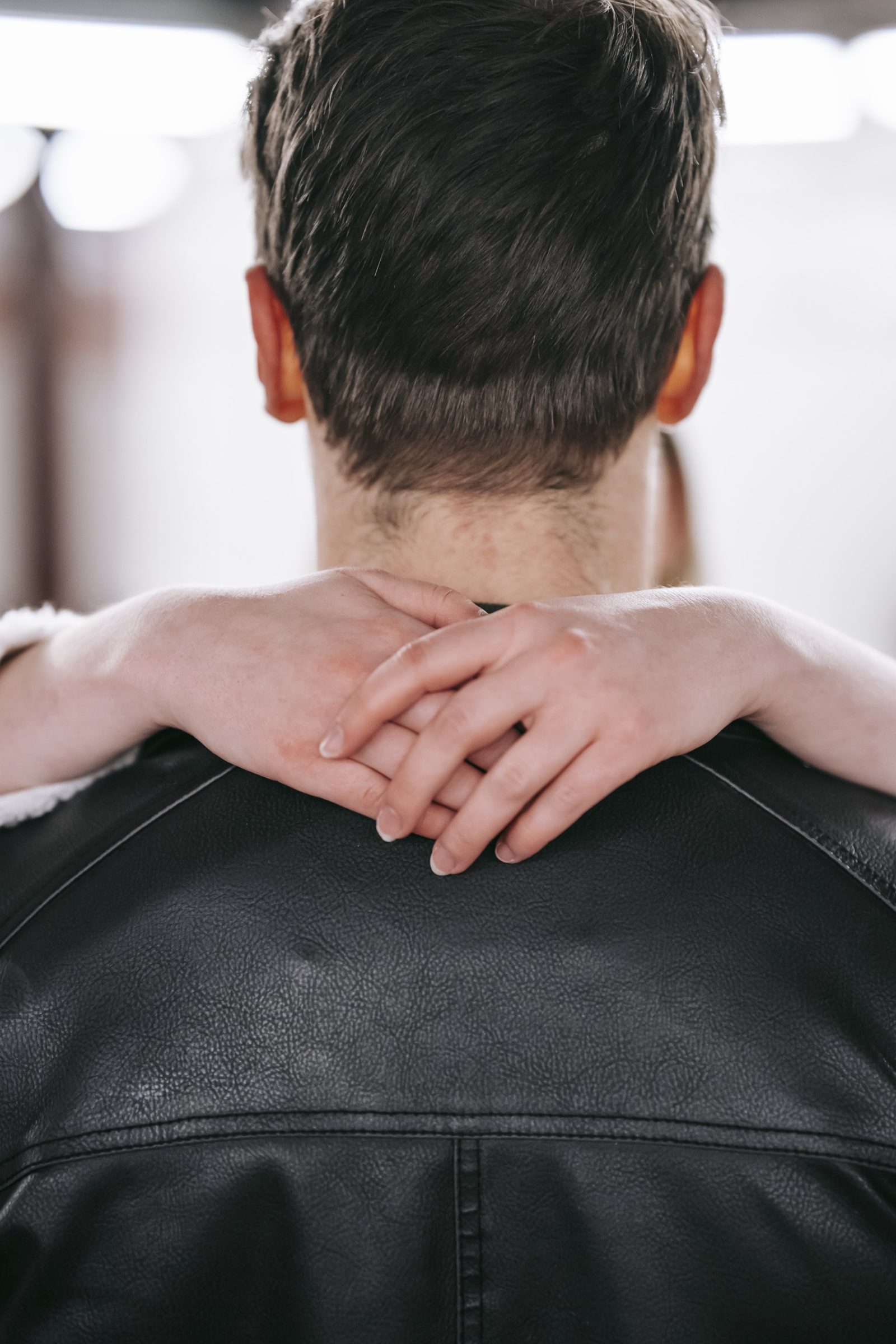 A woman is hugging a man in a leather jacket.
