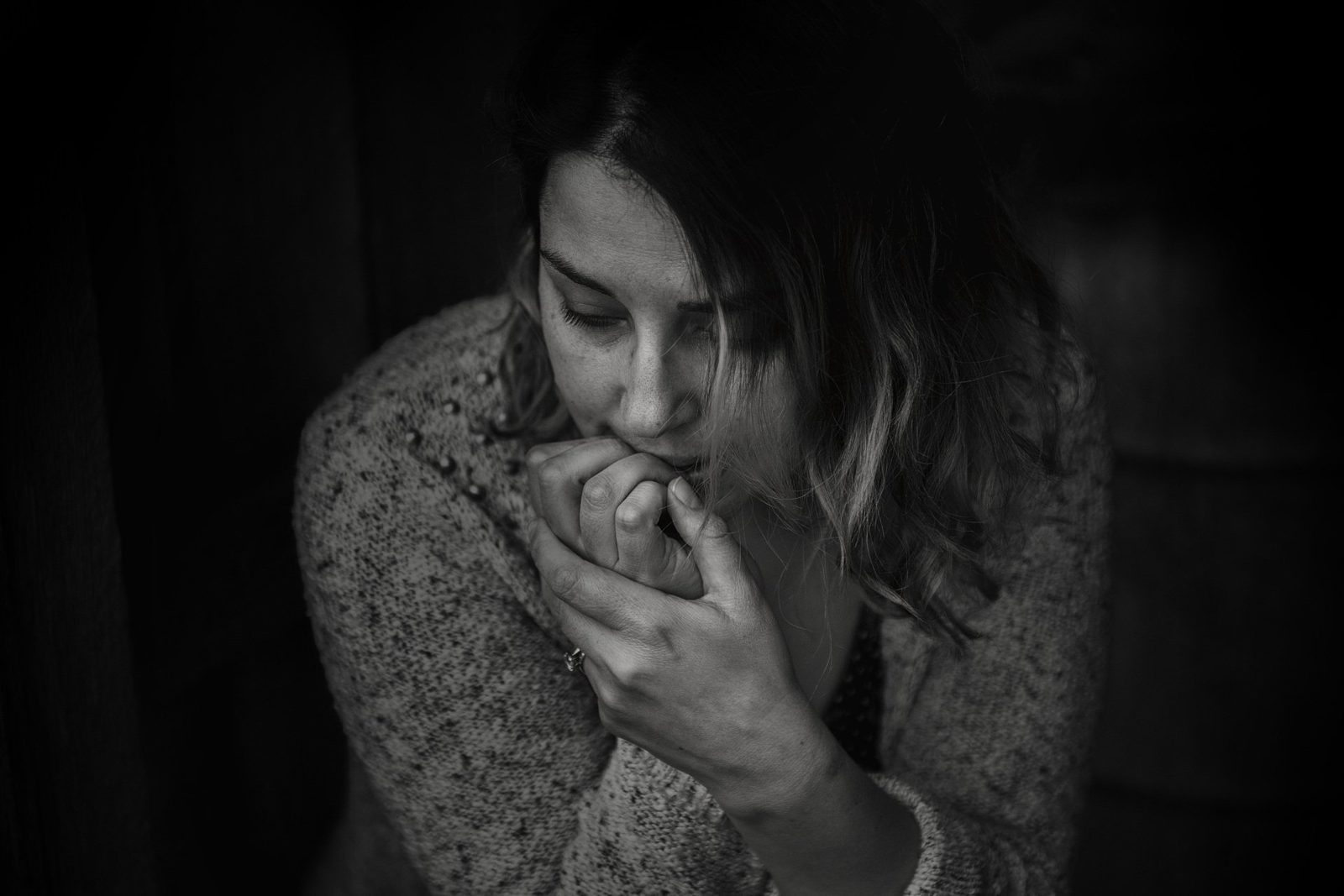 A black and white photo of a woman biting her nails.