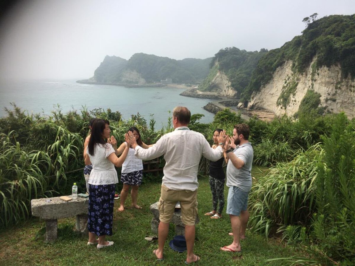 Retreat participants facing one another on a cliff above the sea