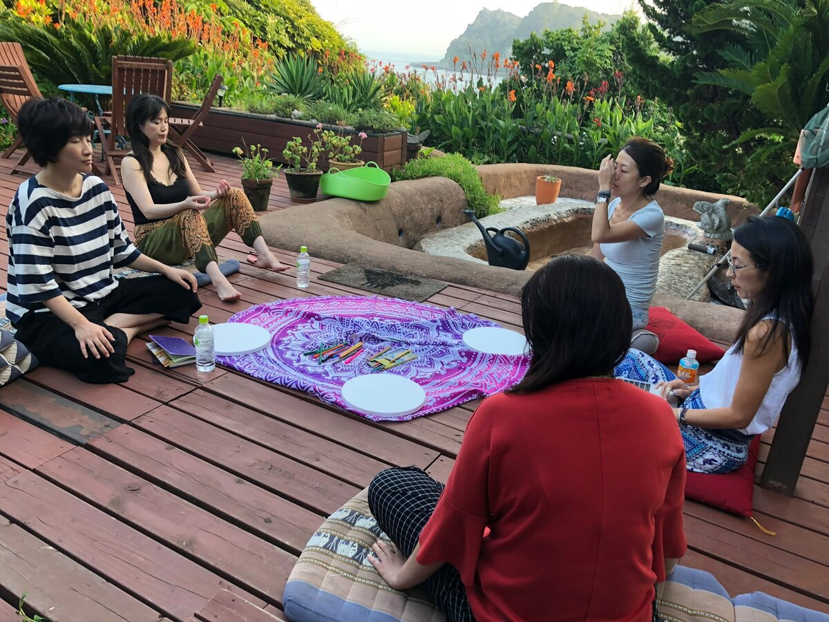 A workshop circle gathered outdoors on a garden deck