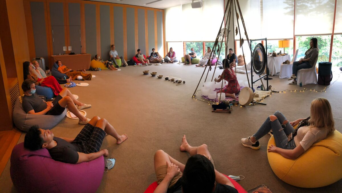 A sound bath session with gongs and participants resting on floor cushions