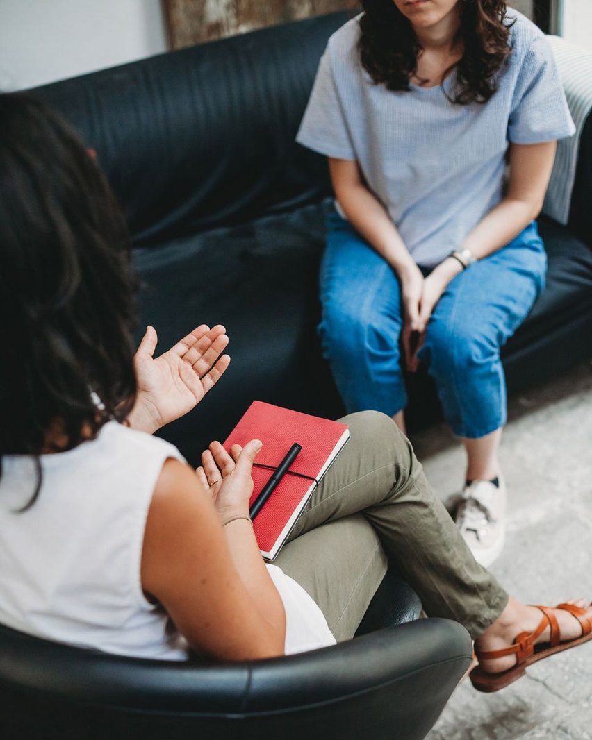 A counsellor with a notebook listening to a client seated opposite during a session